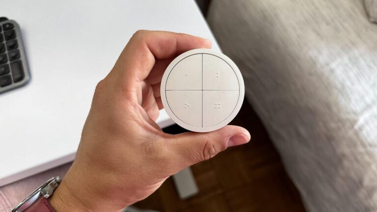 hand holding philips hue tap switch above a desk surface