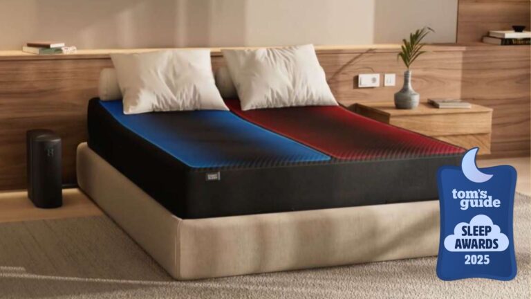 The Eight Sleep Pod 4 smart mattress cover on a nude bedframe with bedside control hub to the left and white pillows on bed with wooden panel in background with Tom's Guide Sleep Awards 2025 logo