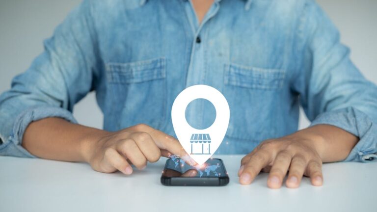 A person uses a phone with a home address location icon emerging from it.