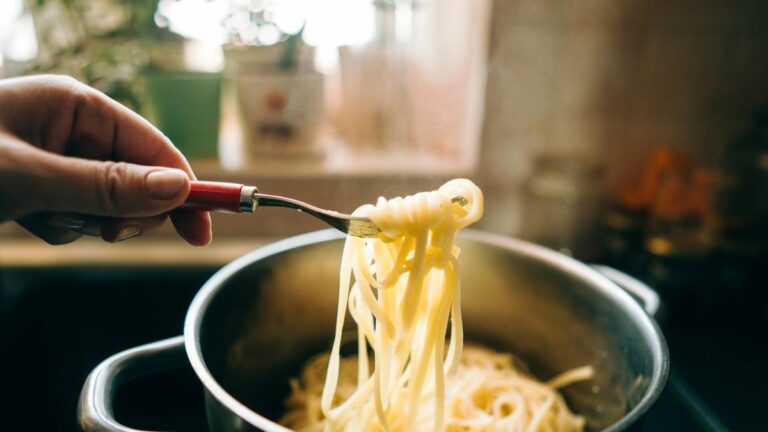 person twirling pasta out of colander