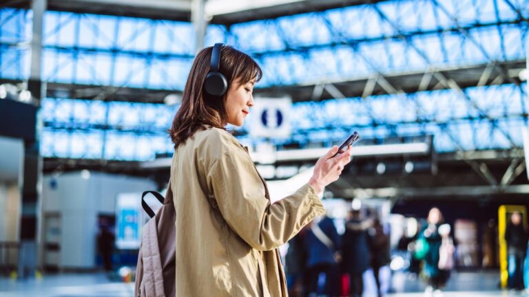 Sick of Your Wireless Headphones Cutting Out? Here’s What I Do to Stop It A businesswoman having video call with smart phone and wireless headphones at an airport.