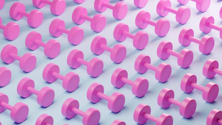 AI as a Muscle Building Coach: How It Stacks Up Against a Real Trainer An image showing a series of pink dumbells laid out on a white background (gettyimages-1886169763)